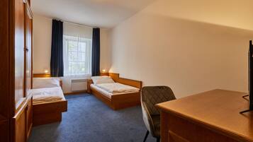 A room with two single beds, a desk, and a chair.