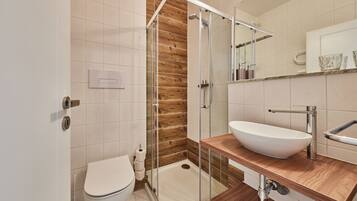 A modern bathroom with a glass-enclosed shower, a wooden vanity, and a white sink.