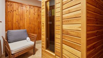 Una sauna de madera con un banco y una puerta de vidrio.
