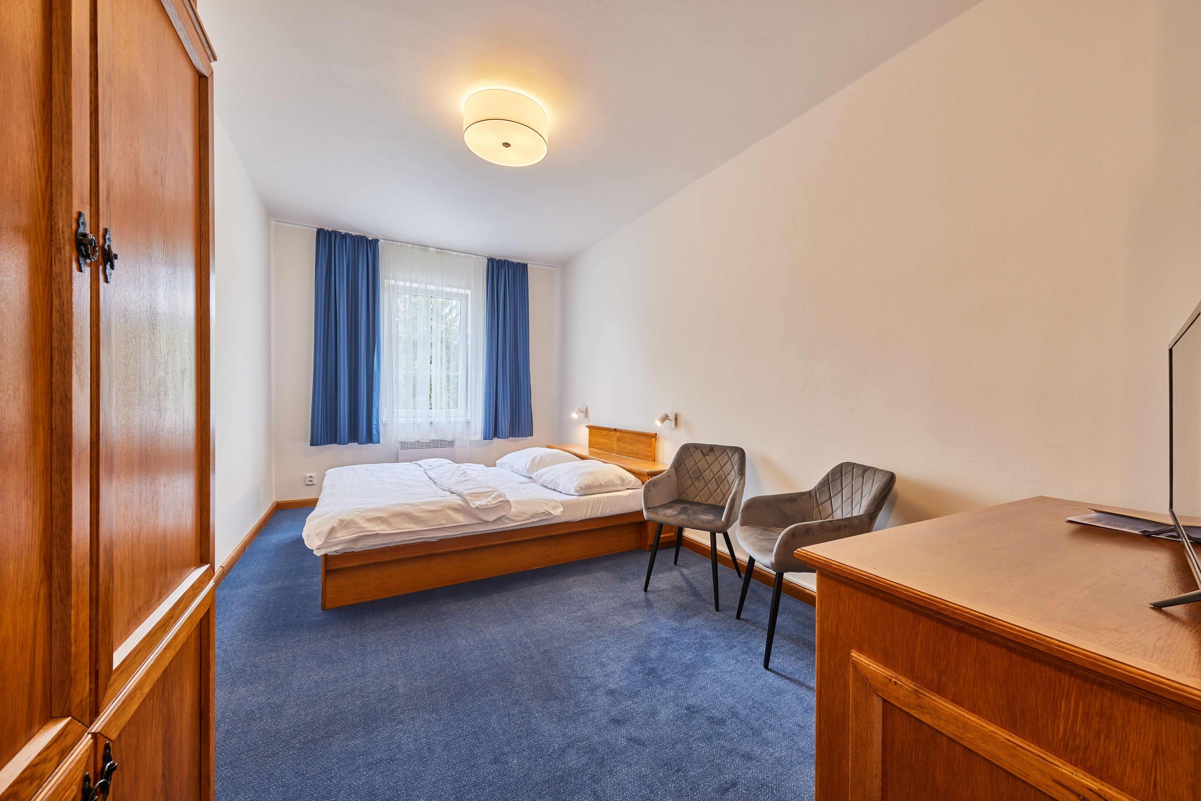 Ett hotellrum med en säng, ett skrivbord, en stol och en garderob.