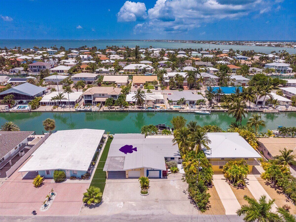 Uma área residencial costeira com casas, um porto de iates e uma vista clara do oceano.