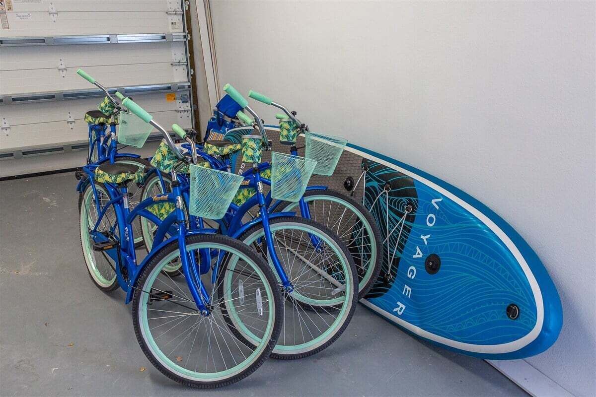 A blue bicycle with a matching blue surfboard leaning against a wall.