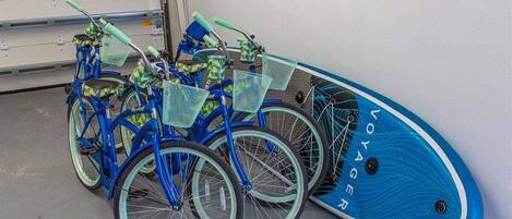 A blue bicycle with a matching blue surfboard leaning against a wall.