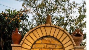 A stone-built outdoor water feature with a central fountain, surrounded by a stone border and potted plants. - Χαλαρώστε σε ένα ιδιωτικό μέρος 1χλμ απ'τη θάλασσα (Gargalianoi)