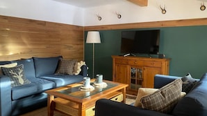 A cozy living room with a blue sofa set, a wooden coffee table, and a television on a wooden cabinet. - Ferienwohnung Kaiserin (Reit im Winkl)