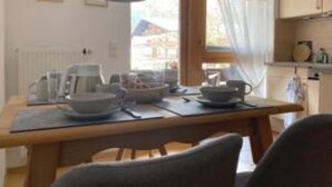 A dining area with a wooden table set for two, a kettle, and a coffee pot. - Ferienwohnung Kaiserin (Reit im Winkl)