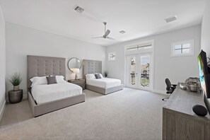 Een moderne slaapkamer met twee bedden, een bureau en een balkon.