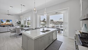 Una cocina moderna con una isla grande, armarios blancos e iluminación colgante.