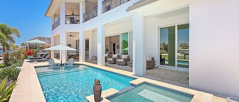 A modern two-story house with a swimming pool, outdoor furniture, and a balcony.