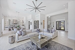 A spacious living room with a large sectional sofa, a coffee table, and a modern ceiling light fixture.