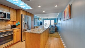 A modern kitchen with wooden cabinets, stainless steel appliances, and a large island.