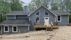 A two-story house with a covered porch, a chimney, and a gravel driveway.