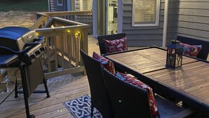 A deck with a grill, outdoor furniture, and a patterned rug.