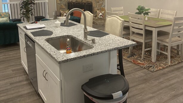 A modern kitchen with granite countertops, a built-in dishwasher, and a black trash bin.