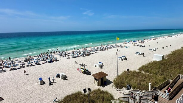 A beach with sun loungers, umbrellas, and a lifeguard tower. - Gulf Front 3rd Floor Perfect Location Free Beach Chairs! Free Golf Everyday! (Panama City Beach)