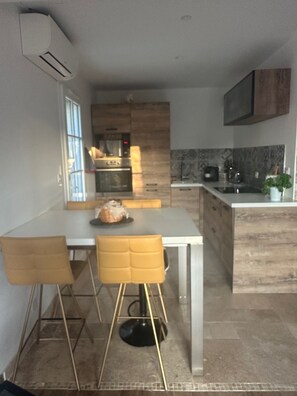 A modern kitchen with a central island, built-in oven, and a dining area with a table and chairs.
