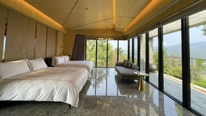 A modern bedroom with a large bed, a sofa, and a view of the outdoors. - The Forest Museum (Zhuolan)