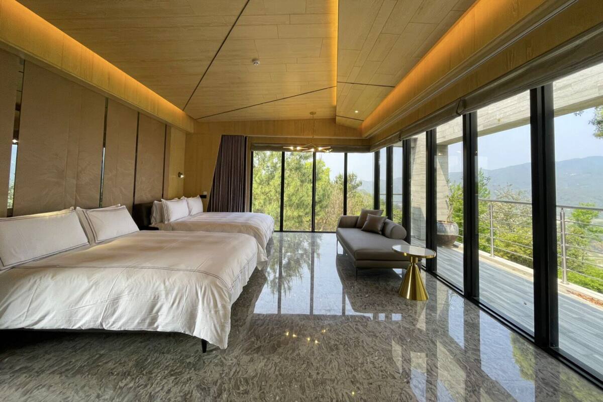A modern bedroom with a large bed, a sofa, and a view of the outdoors.