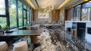 A modern living room with a large sectional sofa, a marble floor, and a dining area with a kitchen counter. - The Forest Museum (Zhuolan)