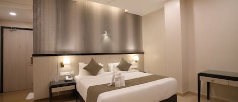 Camera d'albergo con un letto grande, due comodini, una scrivania, una ventola a soffitto e un muro decorato.