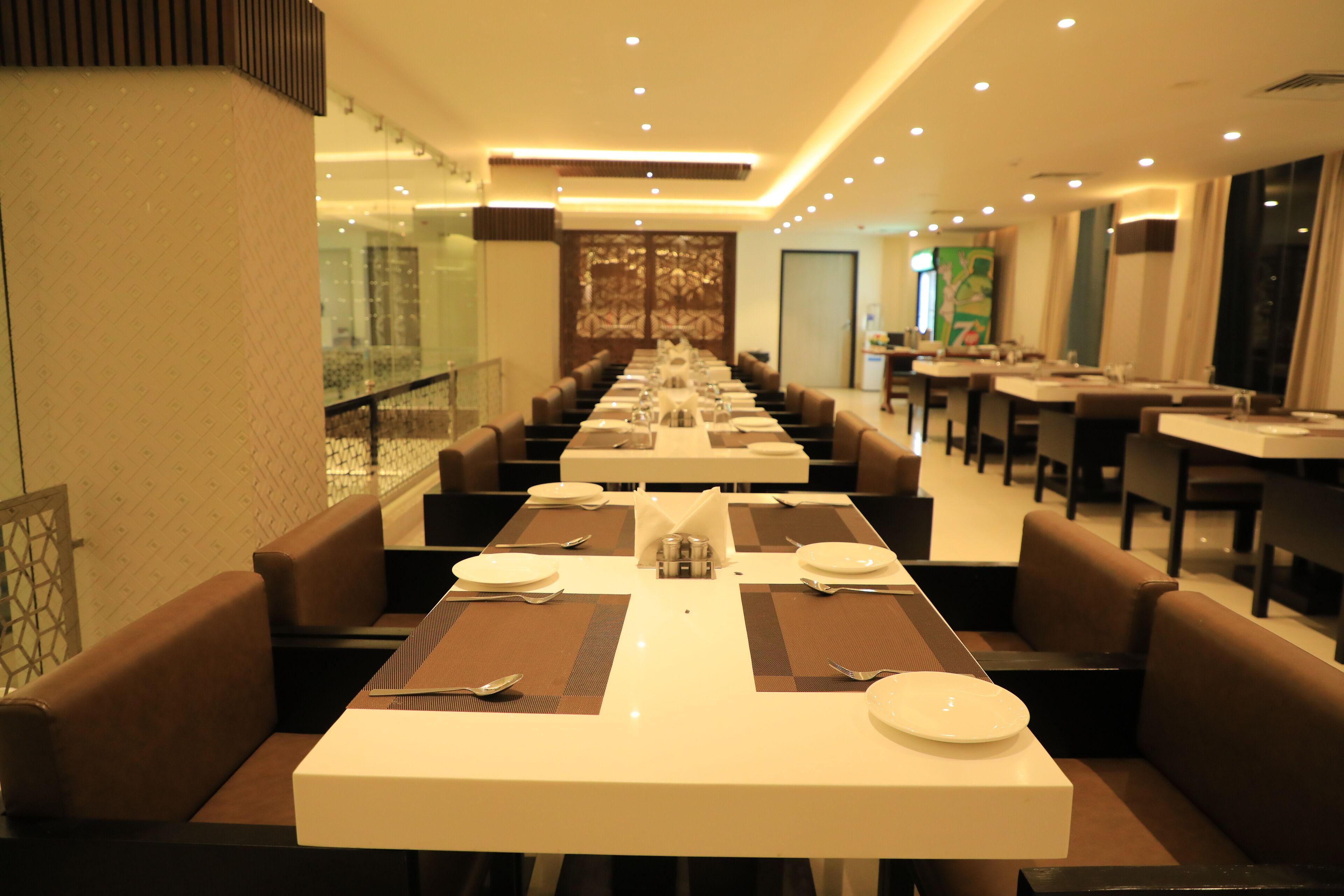 A long dining area with tables set for multiple guests, featuring a modern design with neutral colors and ample lighting.