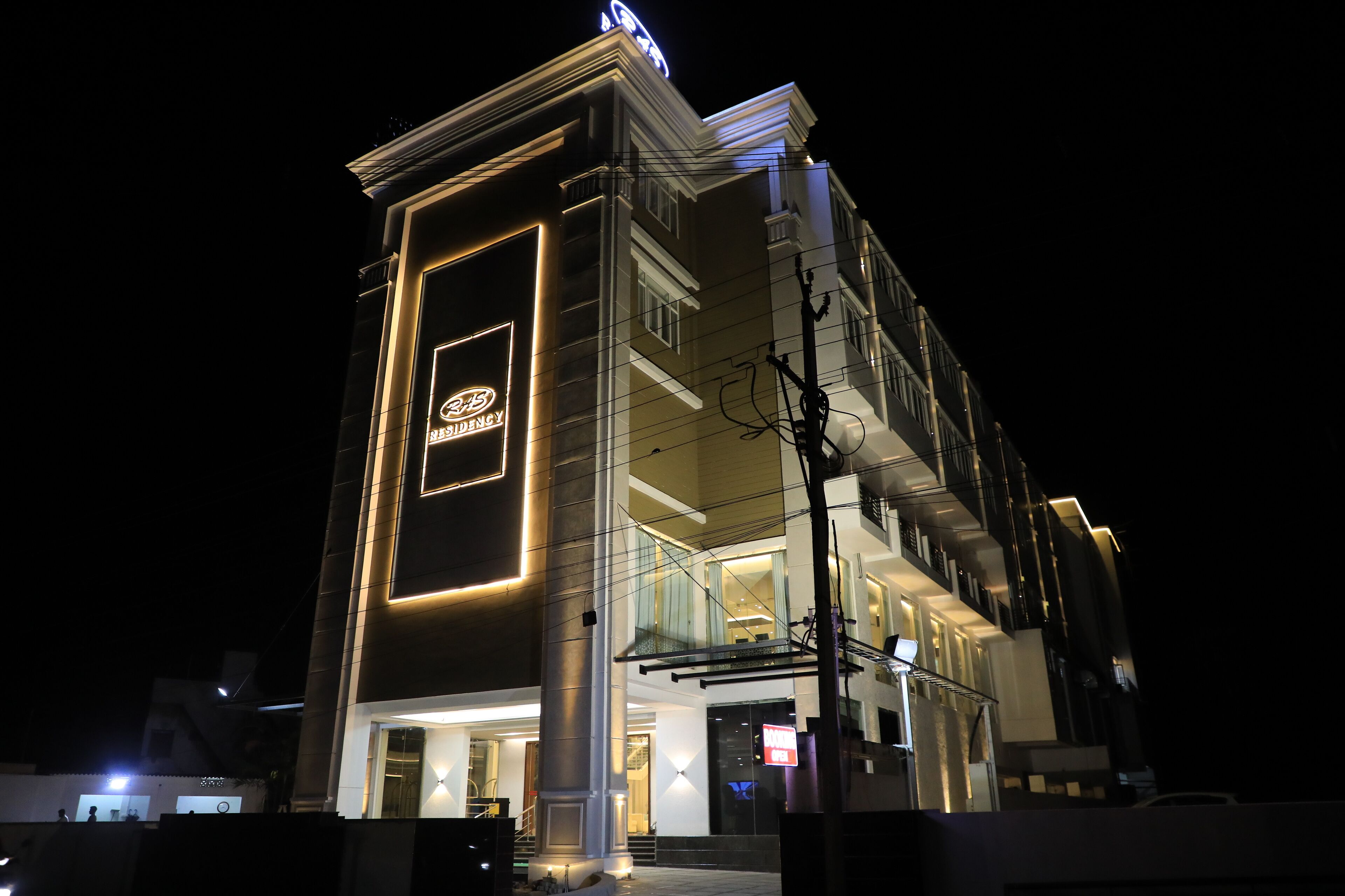 A modern hotel with a prominent 'R5' sign, a glass facade, and a well-lit entrance.
