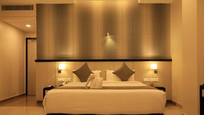 Een hotelkamer met een groot bed, twee bedlampjes, een hoofdeinde met een gestructureerd patroon en een handdoek op het bed.