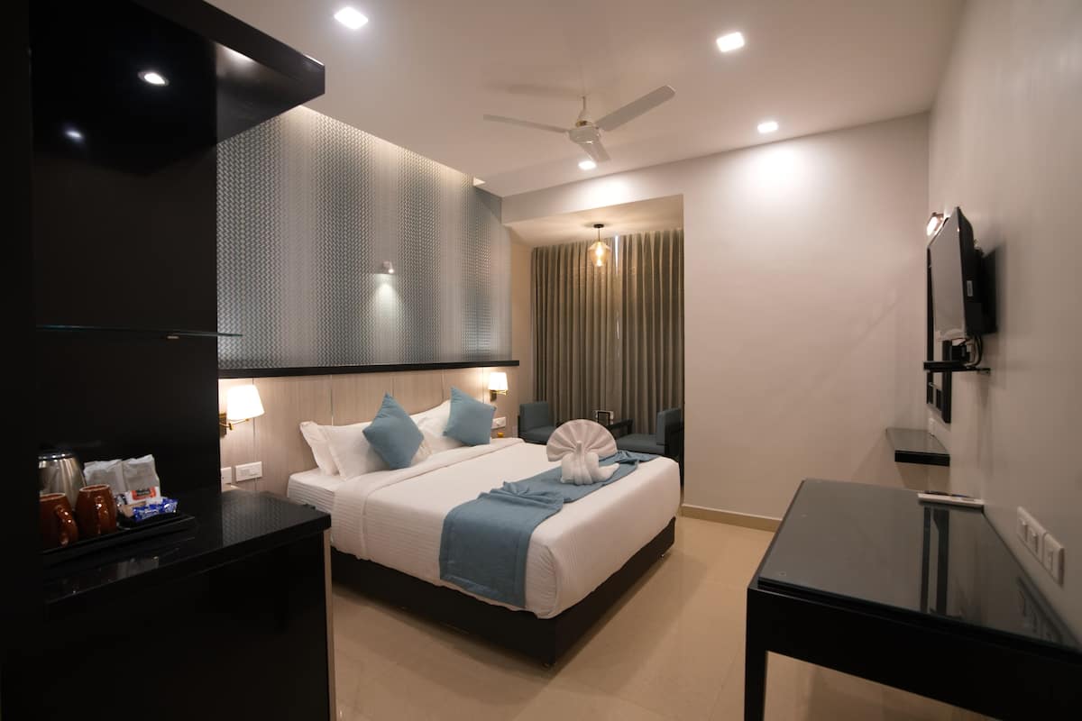 A modern hotel room with a large bed, a desk, a flat-screen TV, and a ceiling fan.