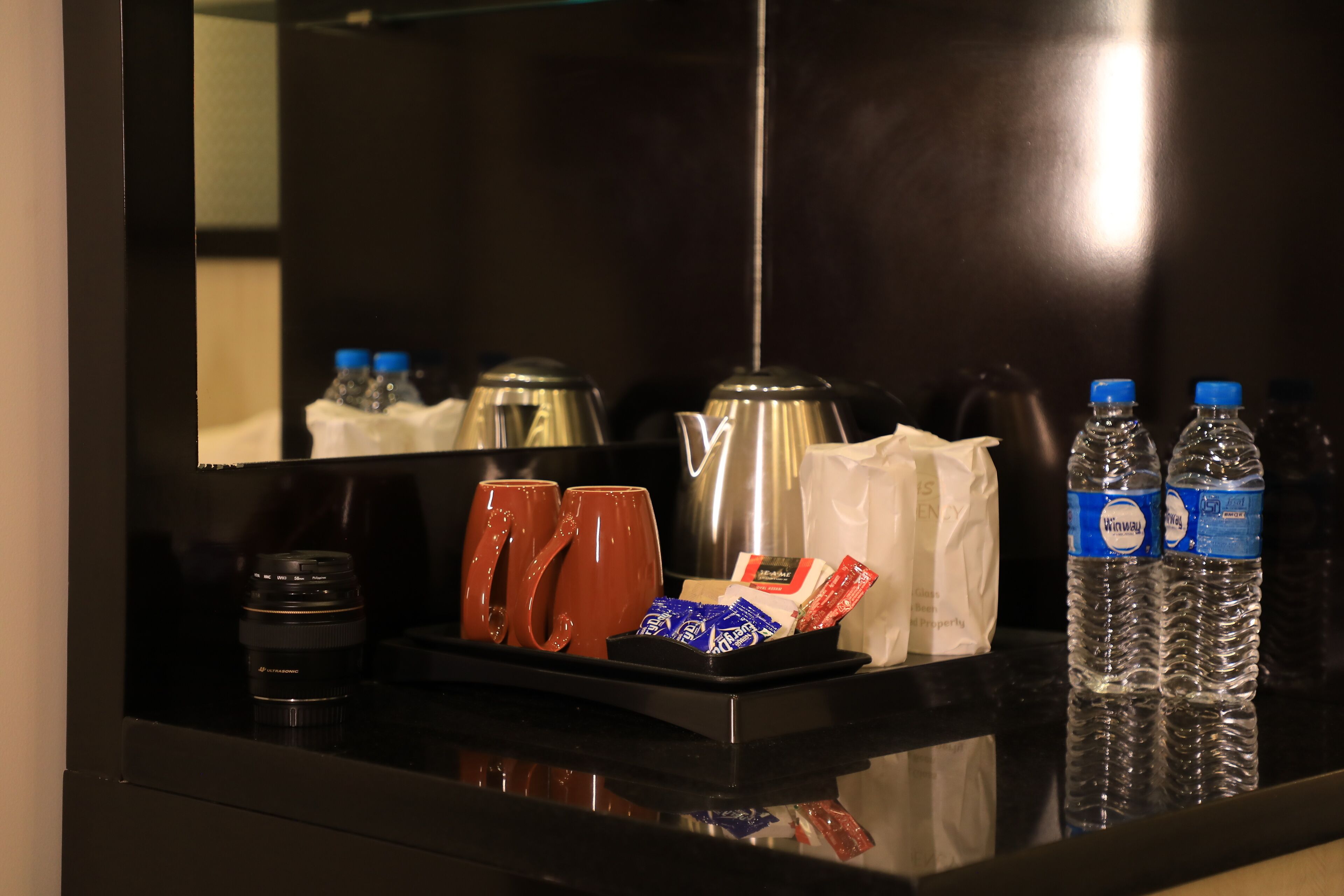 Um minibisco do hotel com cafeteira, duas canecas, água engarrafada e lanches.