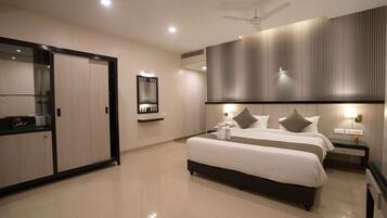 Una habitación de hotel moderna con una cama grande, una mesita de noche, un espejo, un armario y un ventilador de techo.