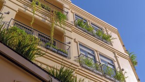 Un edificio de varios pisos con balcones, algunos adornados con plantas.