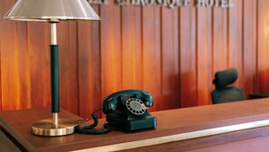 Un mostrador de recepción de madera con un teléfono rotatorio verde antiguo y una lámpara.