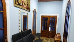 Un pasillo con un sofá, puertas de madera y un cuadro en la pared.