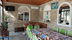 Un comedor con pared de ladrillo, techo de madera y una mesa cubierta con mantel estampado.