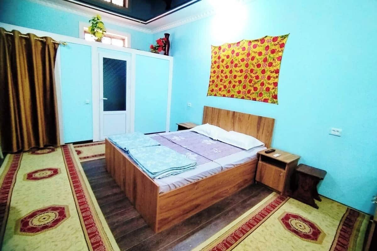 A bedroom with a wooden bed, a nightstand, a wardrobe, and a patterned tapestry on the wall.