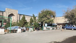 Un estacionamiento con un auto azul, un edificio de techo verde y un letrero que dice "KROPPED SPUR BATHS".