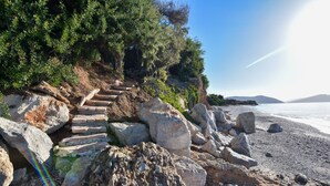 Une plage rocheuse avec un escalier en pierre menant à une zone herbeuse.