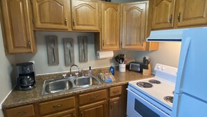 Una cocina con gabinetes de madera, una estufa blanca y un lavamanos.