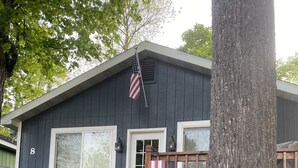 Una casa con un cartel que dice 'WELCOME', una bandera y una pequeña figura de gnomo decorativa.