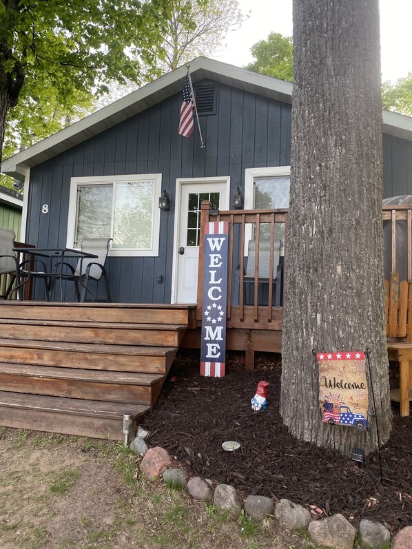Una casa con un cartel que dice 'WELCOME', una bandera y una pequeña figura de gnomo decorativa.
