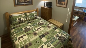 Un dormitorio con una cama, un aparador, una lámpara y dos cuadros en la pared.