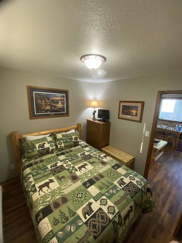 Une chambre à coucher avec un lit, une commode, une lampe et deux tableaux encadrés accrochés au mur.