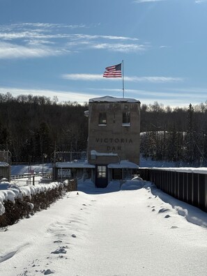 Een betonnen constructie met de tekst 'Victoria Dam', voorzien van een Amerikaanse vlag, omgeven door sneeuw en bomen.
