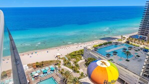 A beach view from a hotel balcony with a pool and lounge chairs. - Rooftop Pool –Oceanview Balcony| Beachfront Resort (Hollywood)