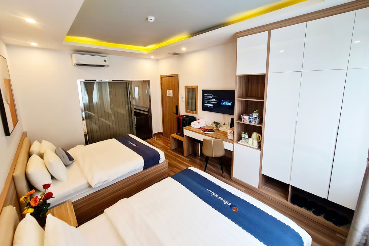A hotel room with two beds, a desk, a TV, and a wardrobe.