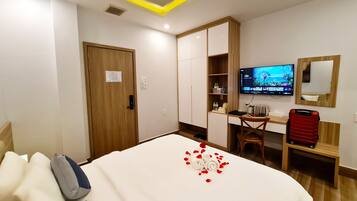 Hotellihuone, jossa on sänky, työpöytä, televisio ja vaatekaappi.