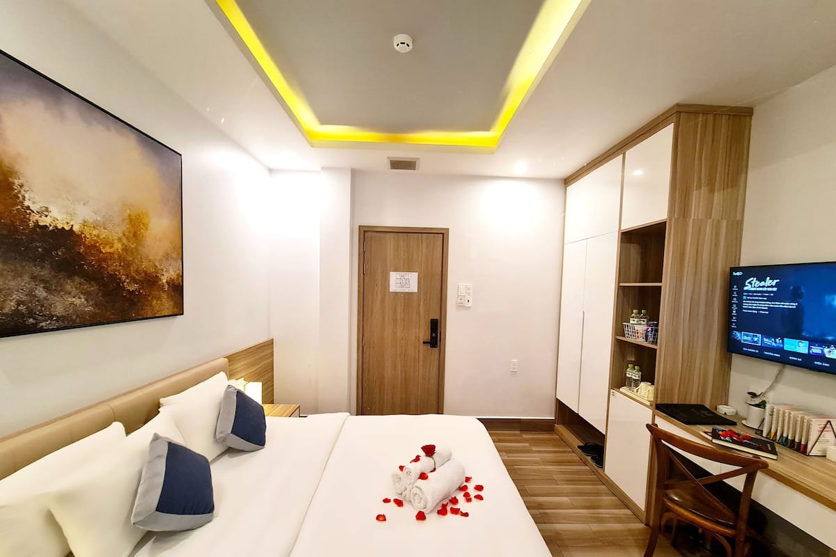 A hotel room with a bed, a desk, a television, and a wardrobe.