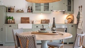 A kitchen with a round dining table, checkered chairs, and a hanging woven light fixture.