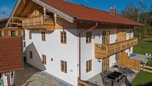 A two-story house with a balcony, a fireplace, and a paved patio area.