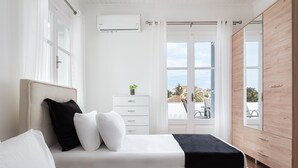 A bedroom with a bed, a dresser, and a window with a view of the outside. - Old Port Spetses Mansion (Spetses)